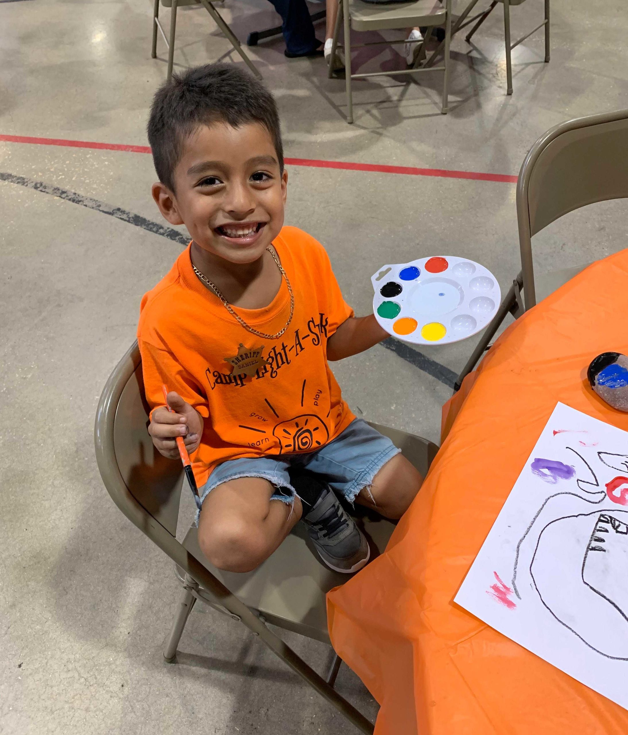 Little boy holding paint & paintbrush