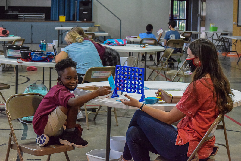 Volunteer playing connect four with student